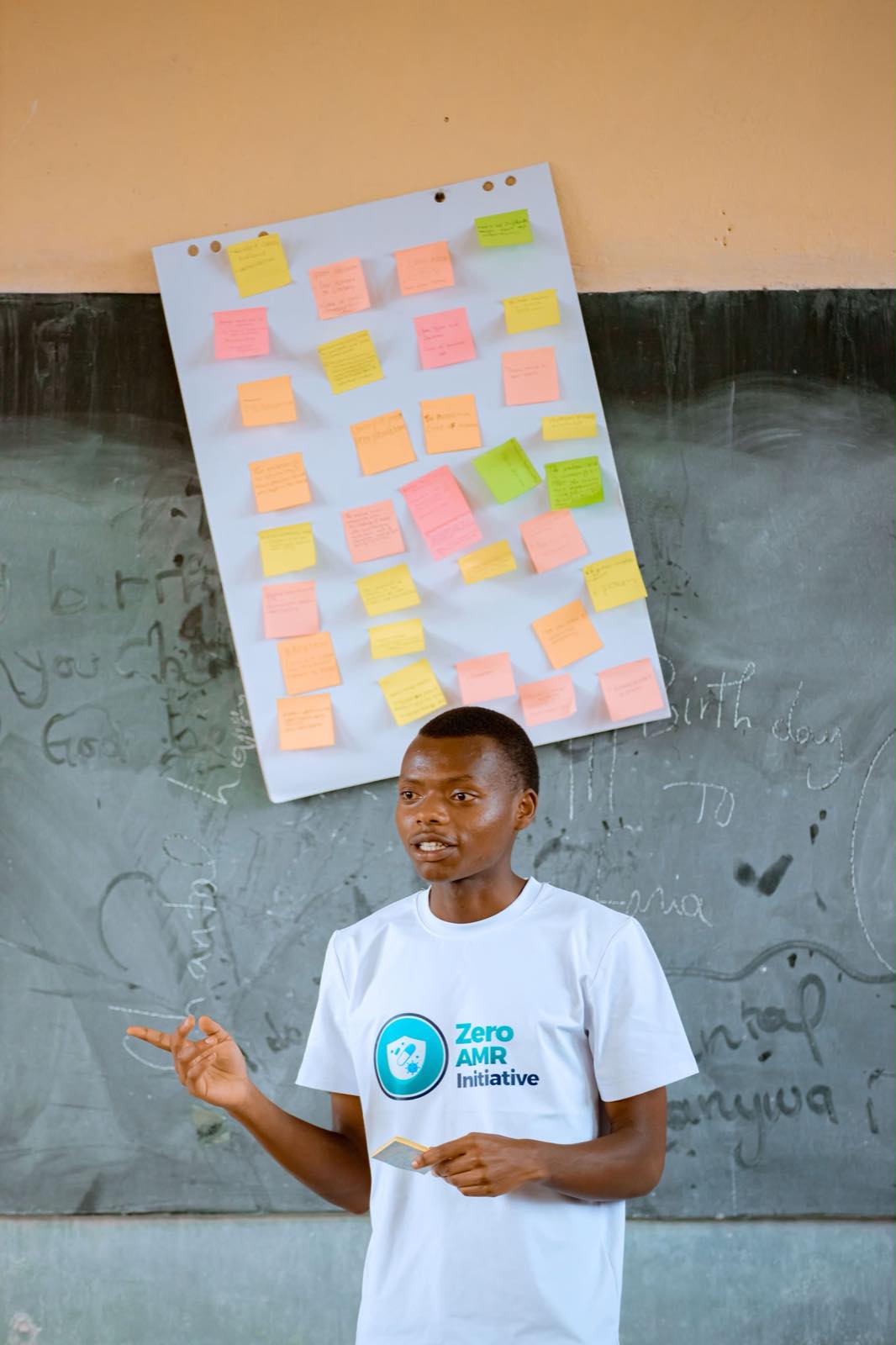 A young facilitator standing beside a flip chart covered in coloured sticky notes during a participatory workshop session