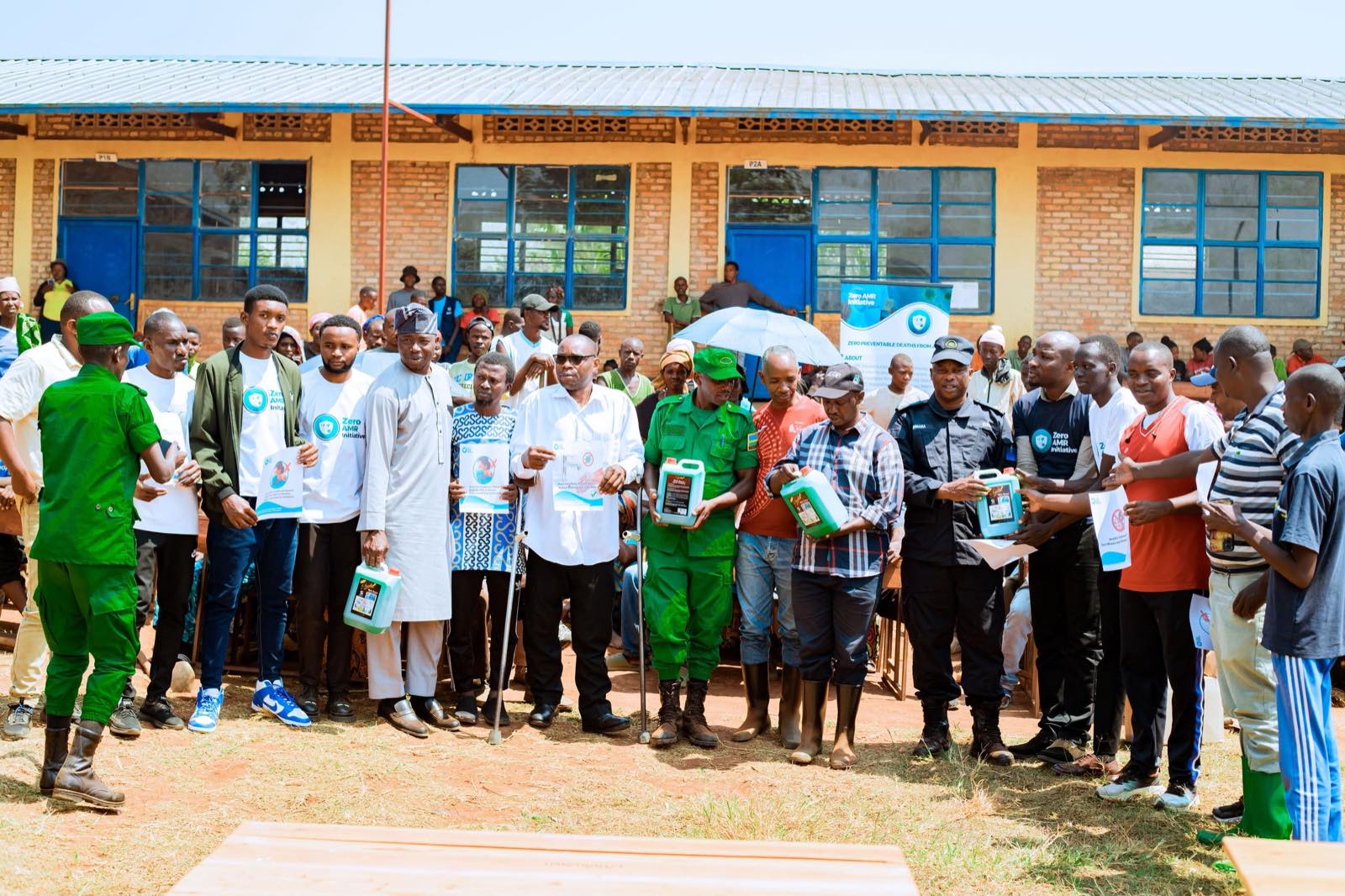 A large outdoor school assembly with students seated in rows listening to a Zero AMR Initiative session